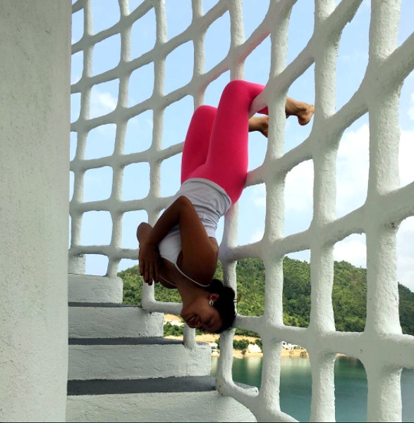 Rachel playfully upside down on a lattice staircase overlooking the water