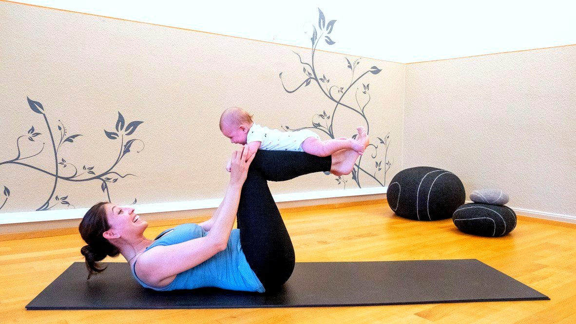 A new mother practicing yoga with her baby balanced on her shins